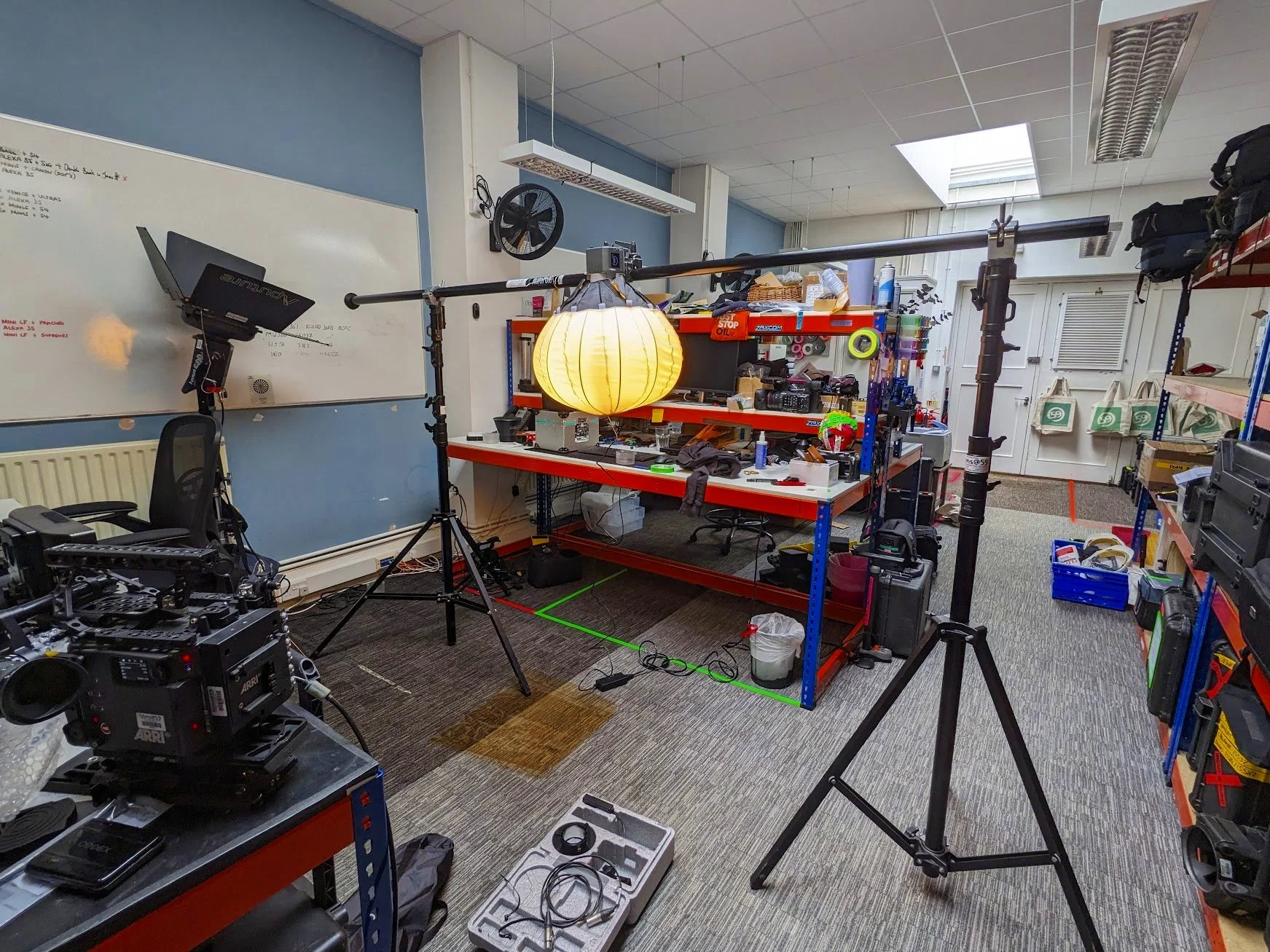 A studio light with a china ball suspended on a scafpole in a workshop.
