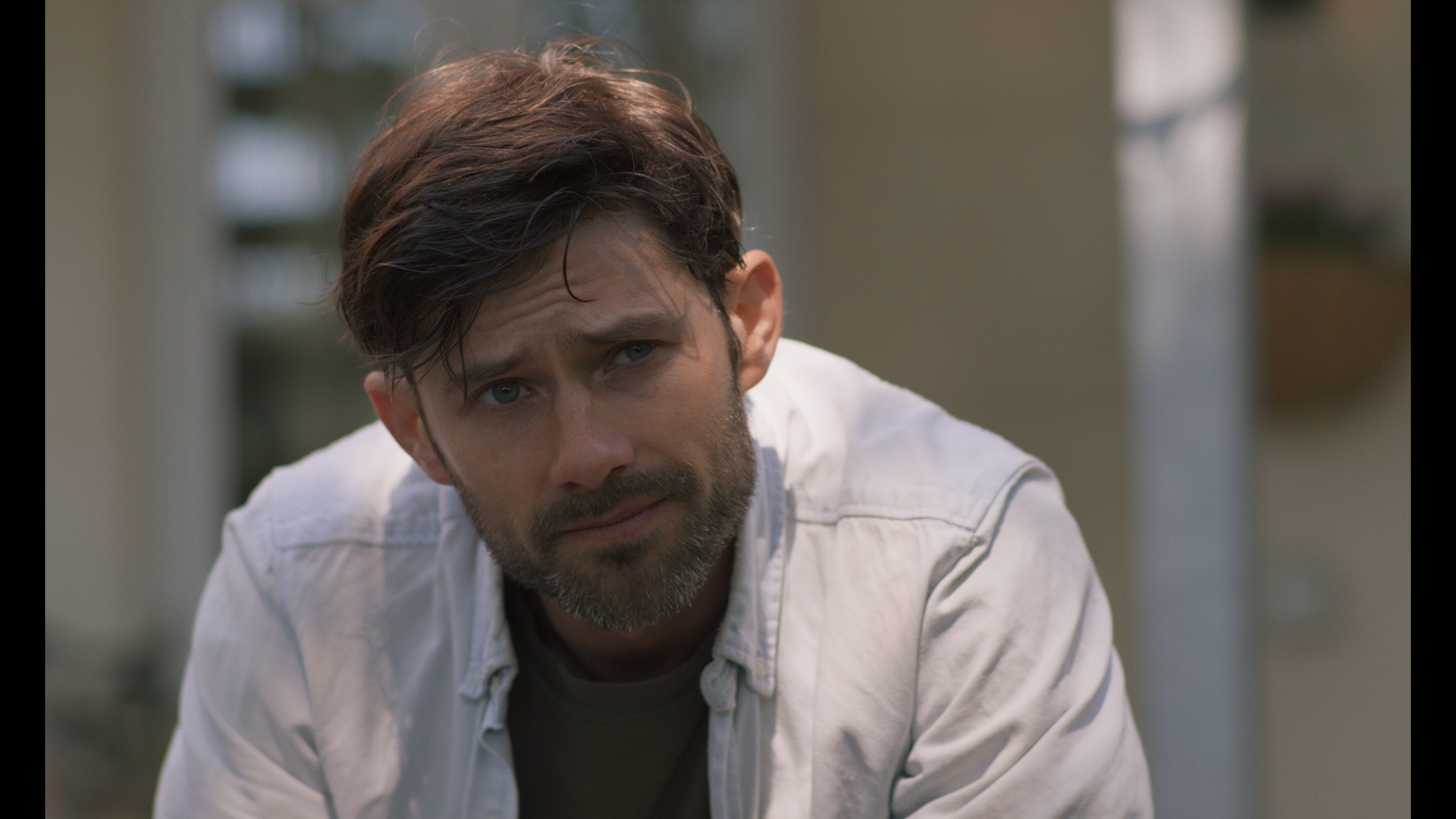 A closeup of a father looking concerned. He is in a garden.